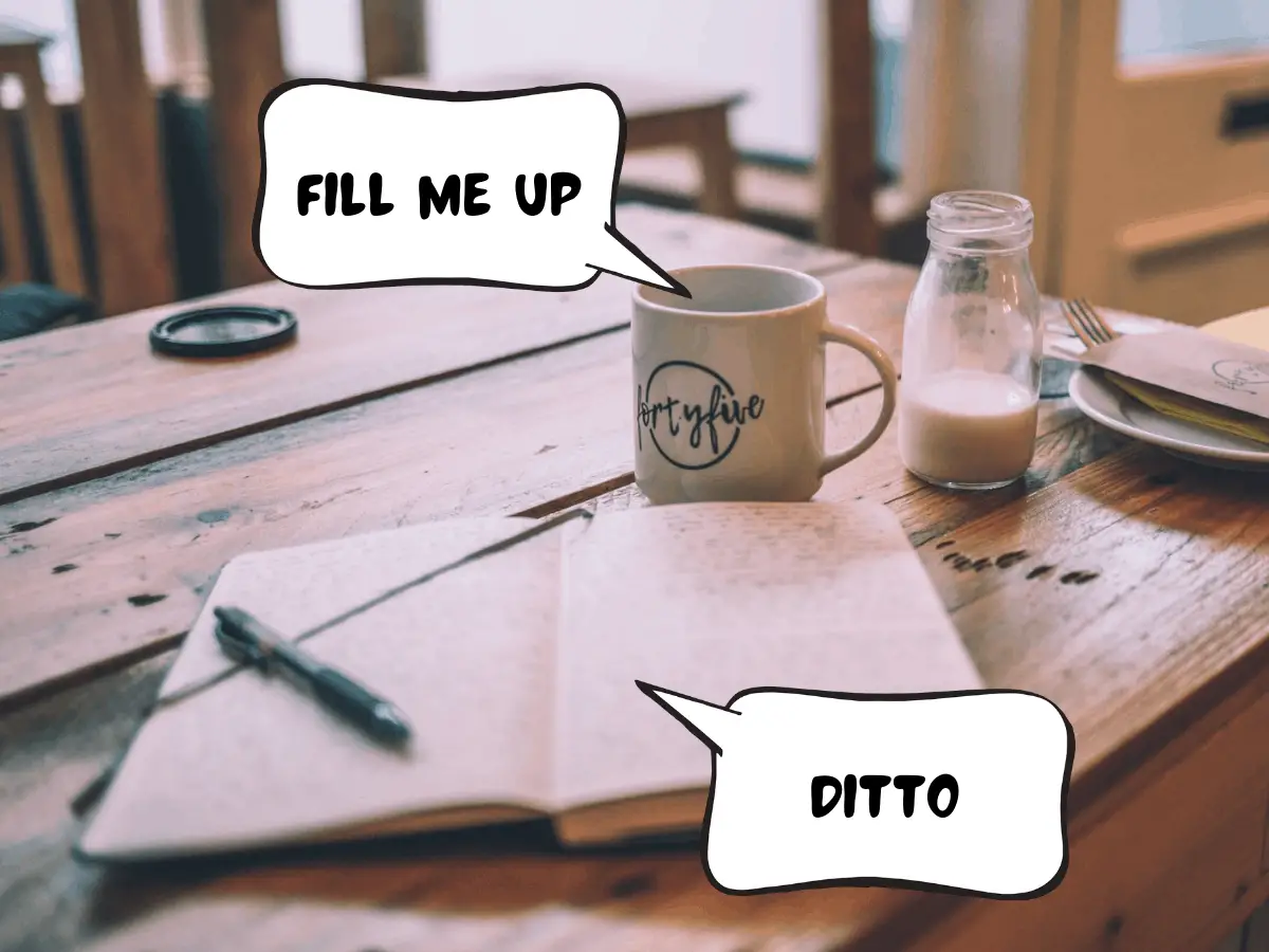 a wooden coffee table with a coffee cup and an open journal. in a comic text bubble, the cup says, "fill me up." the journal says, "ditto"