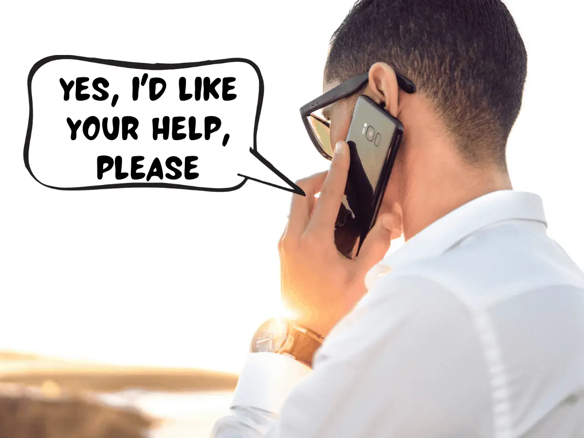 A man is standing over the lake at sunrise or sunset. He is holding up his black smartphone to his ear. In a comic text speech bubble, he says, "Yes, I'd like your help, please."
