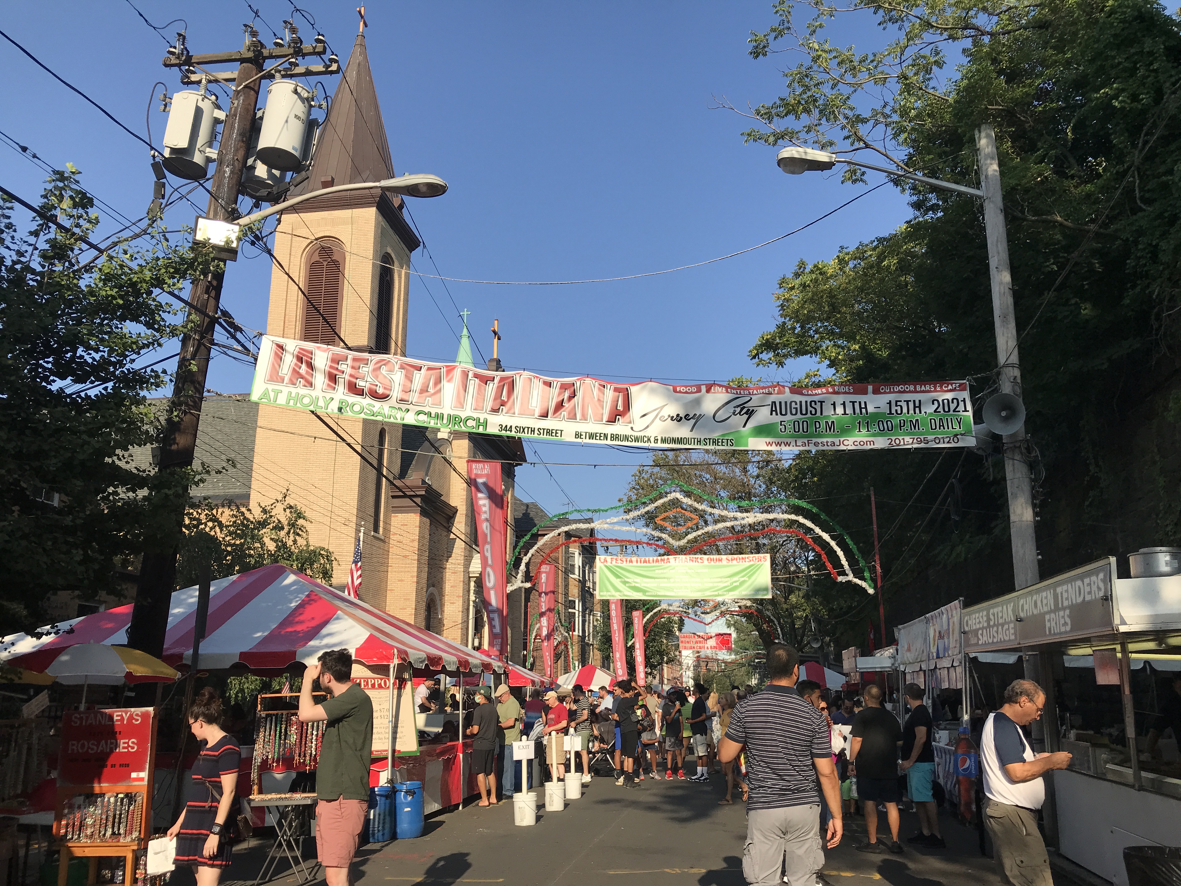 The Italian Festival (or La Festa Italiana) at the base of a church. Banners and street venders line the street. Jersey City, New Jersey, United States