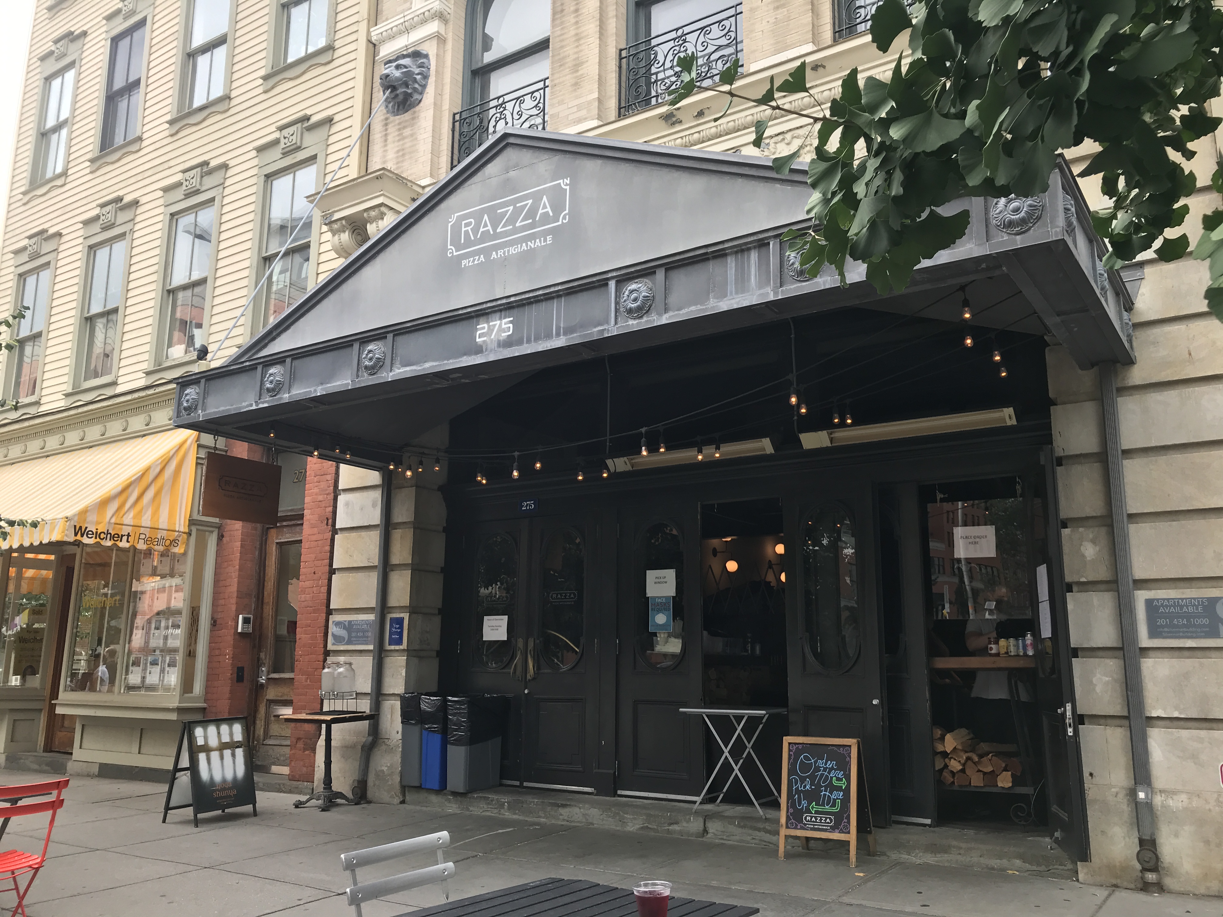 Razza pizzeria has a black metal triangular roof with orders being done at the window. Jersey City, New Jersey, United States