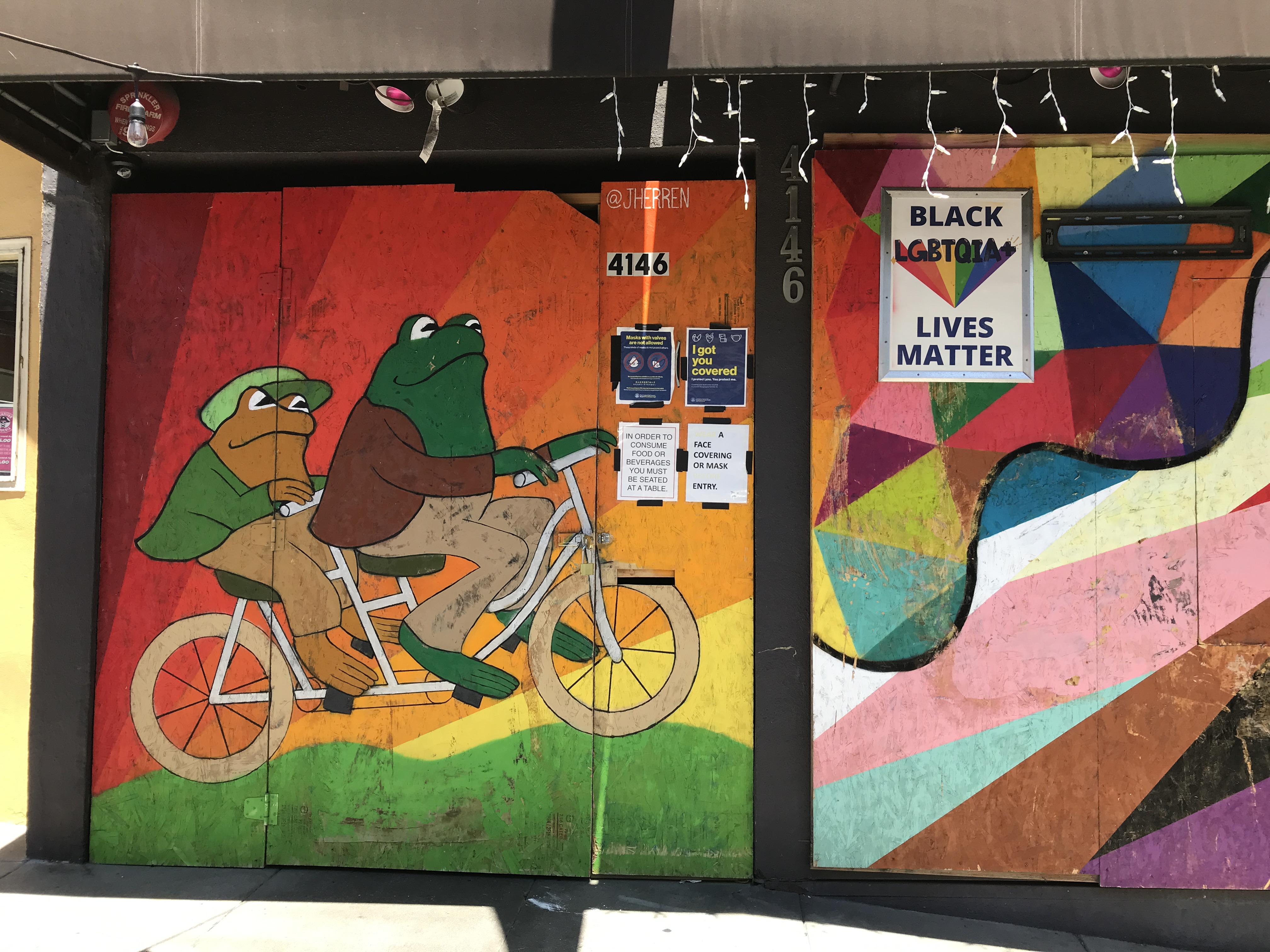 A rainbow mural on a wall featuring the book characters Frog and Toad riding on a bicycle together. The Castro District, San Francisco, California, United States of America