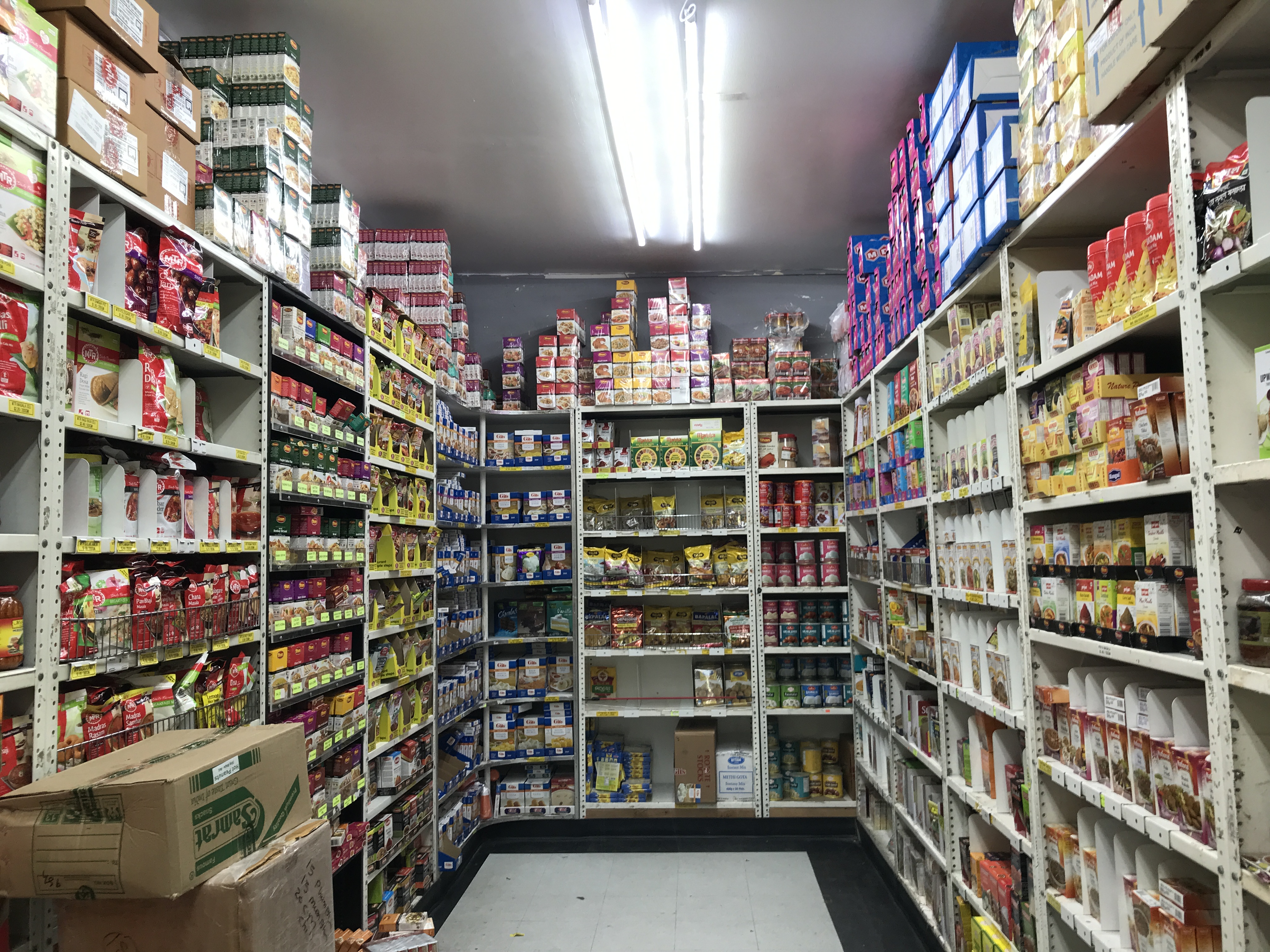 An aisle of an Indian grocery store with many colorful spice containers on the racks. India Square, Journal Square, Jersey City, New Jersey, United States of America