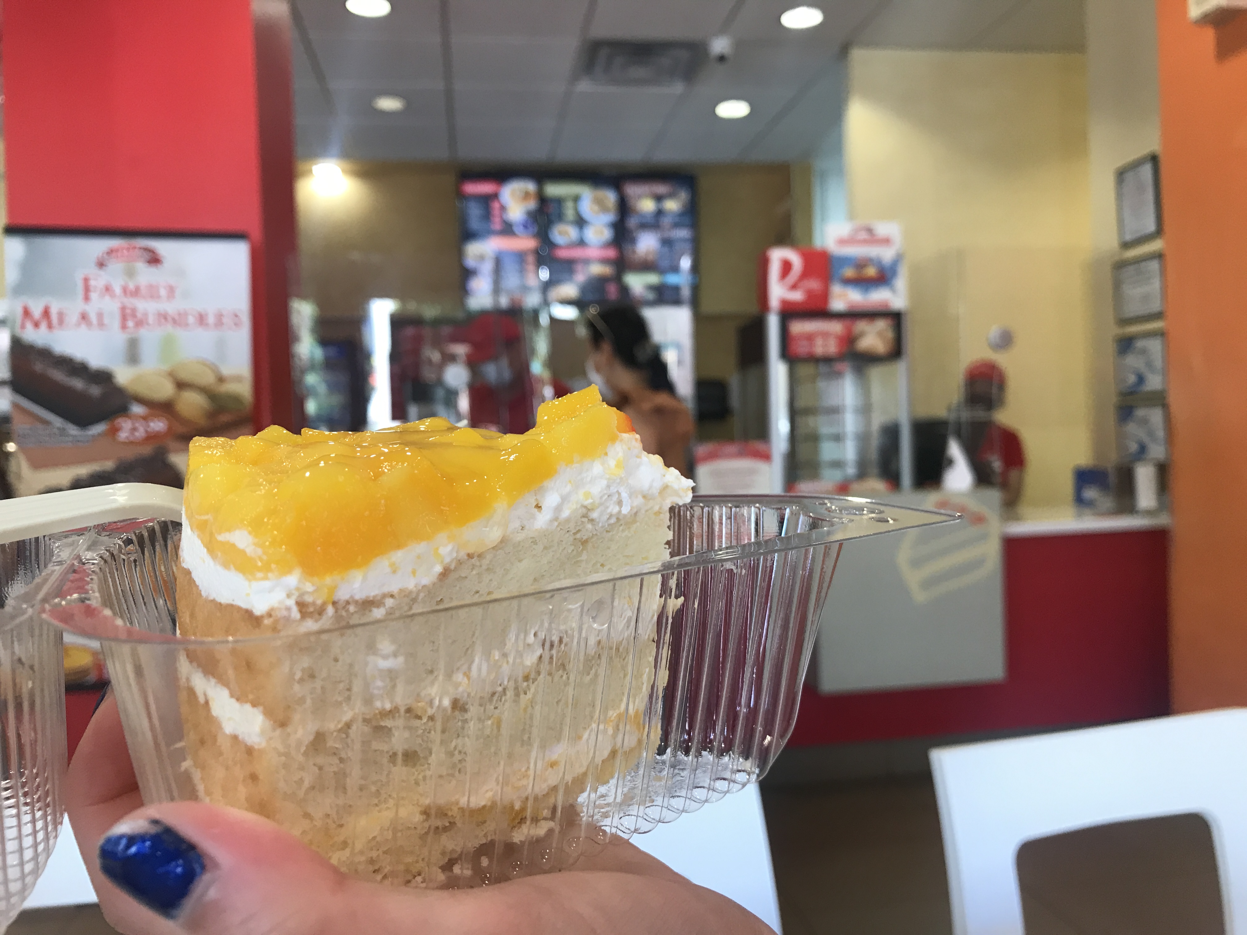 A light yellow slice of Mango Supreme Cake with glazed mango on the top. Red Ribbon bakery, Jersey City, New Jersey, United States of America