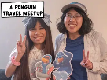 Two penguins from the Club Penguin community, Meggie (Tech70) and Athena (Cw700) meet in real life. Both of them are holding up paper cutouts of their penguins and doing the peace sign with their other hand. Athena is wearing a cute white dress and Meggie is wearing a blue t-shirt and ballcap. Their human outfits have a similar color scheme with their penguin cutout outfits. Jersey City, New Jersey, United States of America