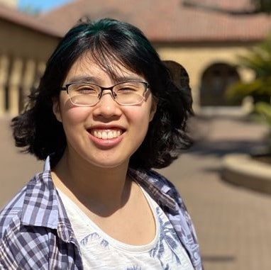 Meggie is smiling with a plaid blue overshirt at Stanford University, California, United States of America.
