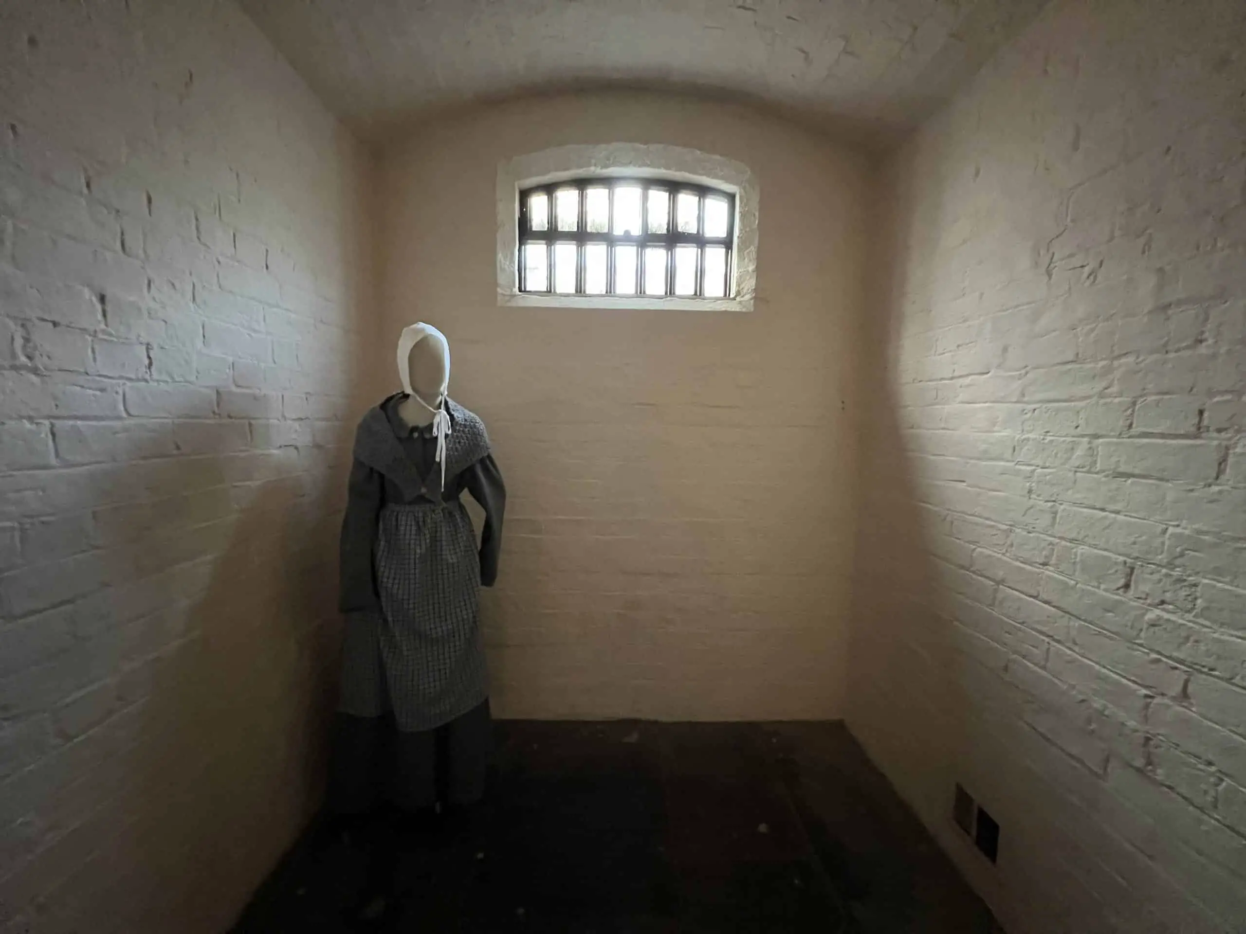 A mannequin of a female prisoner inside a cell, with the sunshine shining through a barred window. " On the grounds of Lincoln Castle, Lincoln, Lincolnshire, England, United Kingdom.