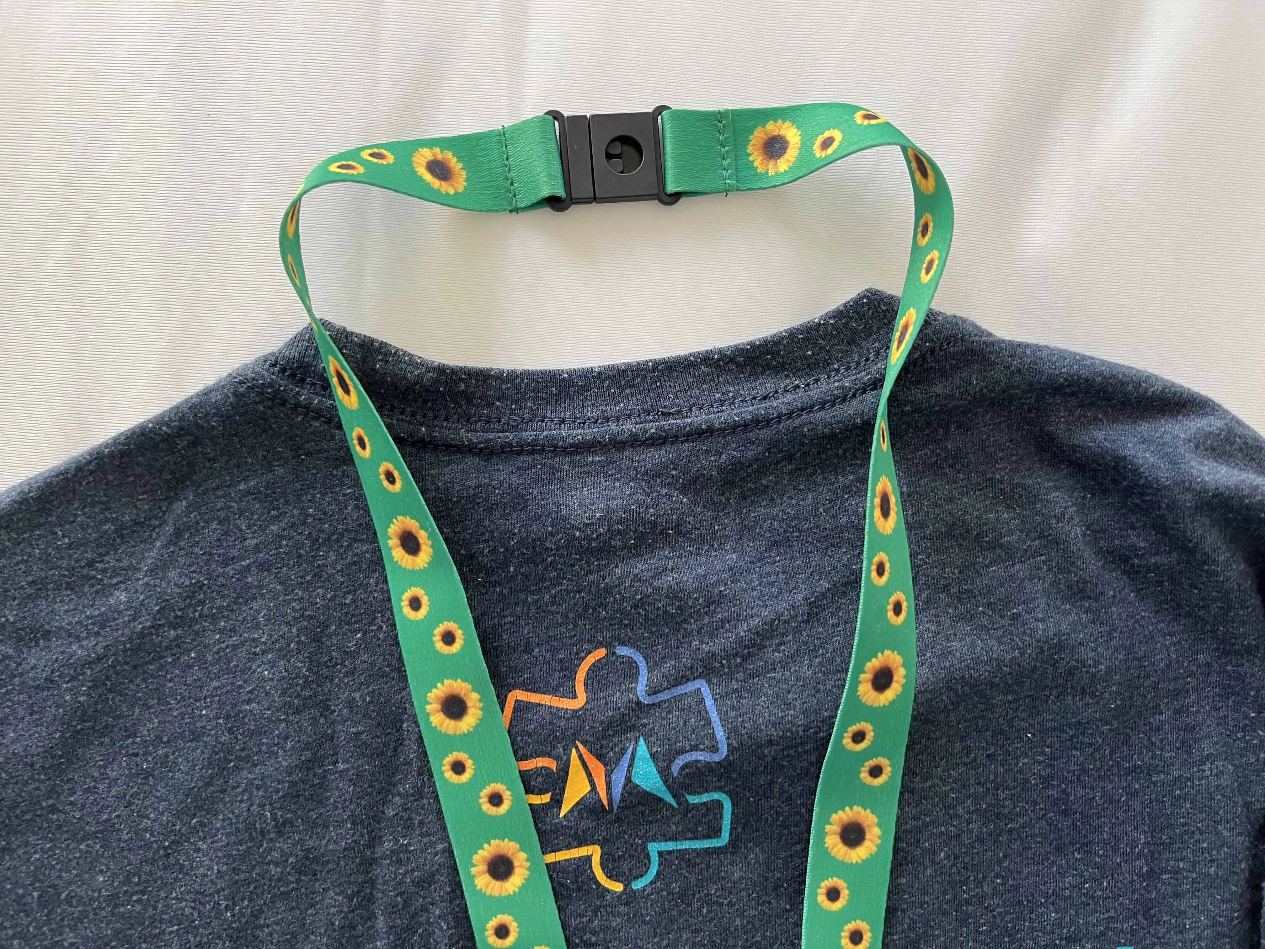 Green Sunflower Lanyard against a Visit Mesa shirt with a puzzle piece representing autism