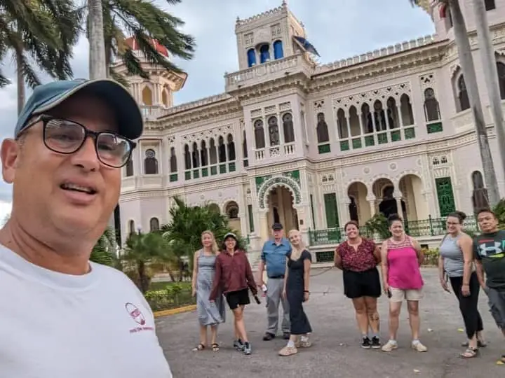 Meggie with their tour group and leader smiling for a selfie in front of a historic house-turned-restaurant nearby Hotel Jagua in Cienfuegos, Cuba.