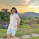 Meggie is smiling in a white shirt in front of an organic farm in Viñales, Cuba during the bright yellow sunset