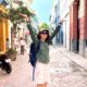Meggie in a green shirt stands in the colorful yellow, red, and blue cobblestone streets of Havana, Cuba,