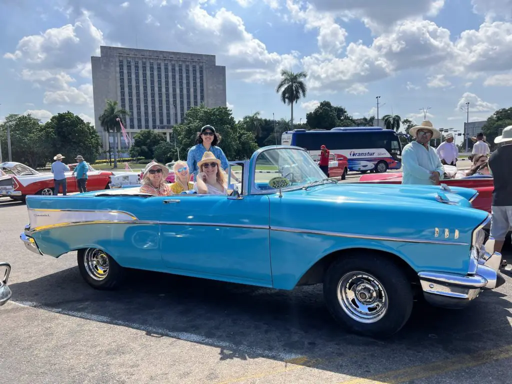 Meggie in a blue vintage American classic car in Revolution Square on a historic car tour through Havana, Cuba.