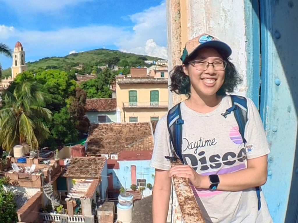 Meggie at a historic bell tower overlooking the brown-roofed buildings of Trinidad, Cuba.