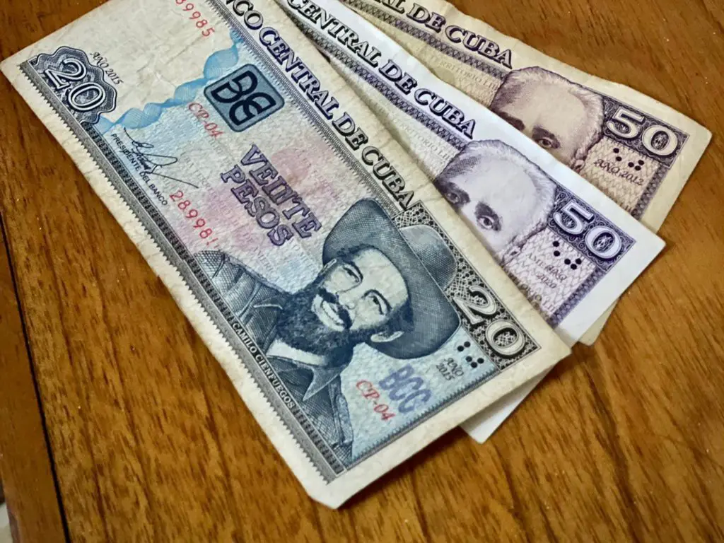 Bills of Cuban pesos on a wooden table in a restaurant. Taken by Meggie's tour made, Jillian