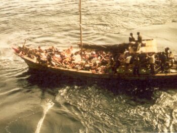 My dad's wooden boat on the sea. A pile of nearly faint people are lying at the bow.